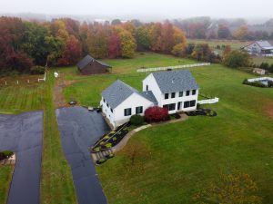 Aerial drone overview of a Chesterfield NJ property with open land, driveway, and surrounding countryside