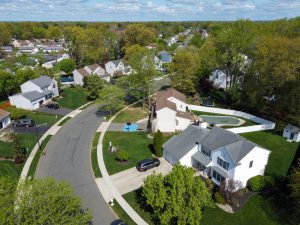 Drone view of a Hamilton NJ neighborhood showing curved streets, surrounding homes, mature trees, and neighborhood layout