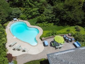 Backyard of a home in Hamilton NJ featuring an inground pool with diving board and landscaped outdoor space