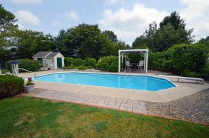 Backyard inground pool with patio and pergola seating area at a New Jersey home