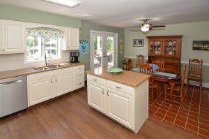 Kitchen in a Hamilton Township NJ home with center island, dining area, hardwood flooring, and natural light