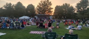 Families and neighbors gather on the lawn at Veterans Park in Hamilton Township NJ for a community concert celebrating America's 250th anniversary.