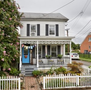 Historic Bordentown City NJ home with covered front porch, blue entry door, picket fence, and landscaped front garden