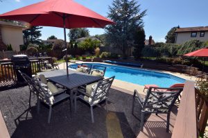 Backyard deck with outdoor dining area overlooking an inground pool at a Hamilton NJ home