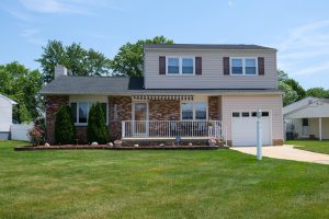 Front exterior of a Hamilton NJ home with covered porch, landscaped yard, and well-maintained curb appeal
