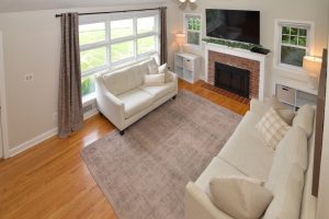 Living room with large windows, hardwood floors, and natural light showcasing a well-presented interior space