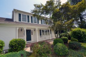Front exterior of a Colonial-style home with covered porch, landscaping, and welcoming front entrance