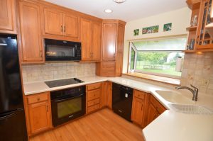 Updated kitchen with custom cabinetry, solid surface countertops, and large window overlooking backyard