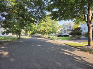 Tree-lined residential street with mature homes and sidewalks in an established Hamilton Township NJ neighborhood.
