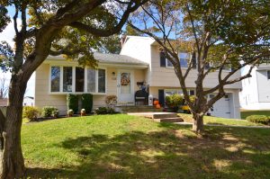Front entrance of a well-maintained Hamilton Township home with clean landscaping, seasonal planters, and subtle fall decorations.