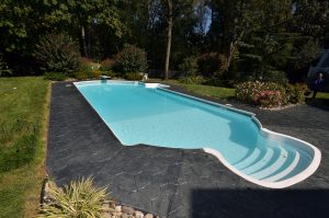 Inground swimming pool with stamped concrete surround, landscaping, and lawn in the backyard of a Bordentown NJ home.