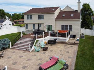 Backyard paver patio and elevated deck creating an outdoor living and entertaining space at a Hamilton NJ home.