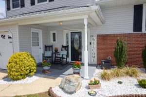Covered front porch with rocking chairs, seasonal flowers, and a welcoming entrance at a Hamilton NJ home.