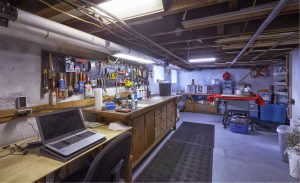 Organized basement workshop in a Lawrence Township NJ home featuring built-in workbench, shelving, and dedicated storage space.