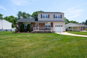 Colonial style home with brick and siding exterior, attached garage, and wide front lawn in an established Hamilton Township NJ neighborhood.