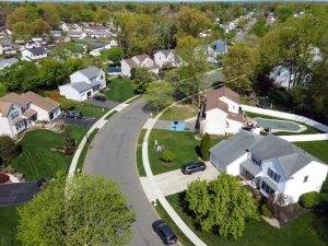 Aerial view of a suburban Hamilton NJ neighborhood with detached homes, curved streets, driveways, and larger residential lots.
