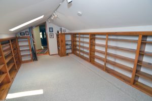 Library in a Yardville Hamilton Township NJ colonial with built-in wood shelving, skylight, track lighting and natural light.