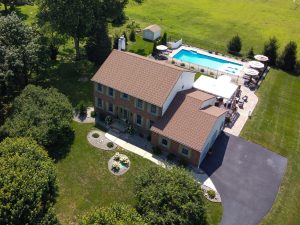 Aerial view of a large colonial home with an expansive property and swimming pool in a more rural section of Yardville in Hamilton Township NJ.