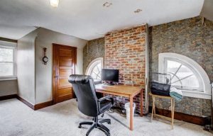 Interior room in an older Roebling NJ home with exposed brick, stone walls, original woodwork, and arched windows.