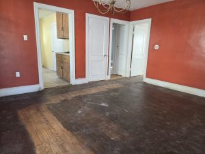 Dining room in a Hamilton Township NJ estate property with hardwood floors, chandelier, red walls and visible wear before an off market sale.