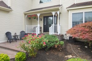Front porch of a Hamilton Township NJ colonial with covered entry, paver walkway, flowering landscaping, and seating area.
